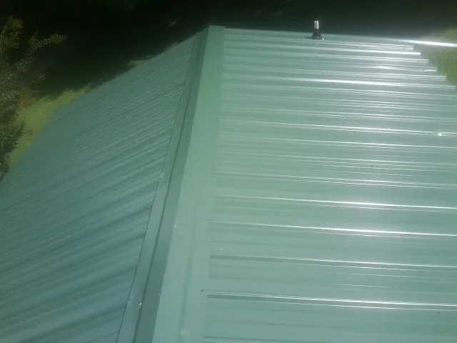 New green metal panels meeting at the ridge of a roof — Flat Roof Repair work by our crew in York