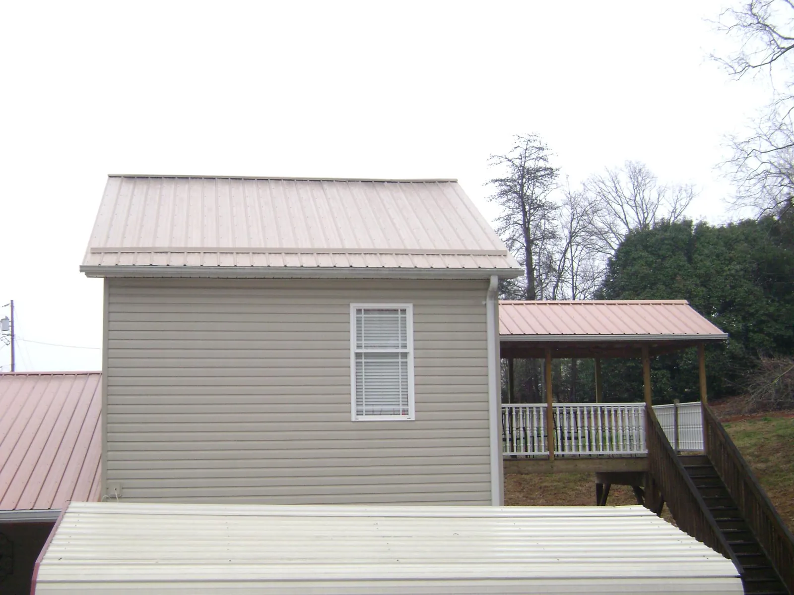 Tan metal roofs on a two story addition and attached porch, from a Roof Replacement job in York